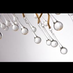 several spoons hanging from the ceiling with drops of water on them and gold colored handles