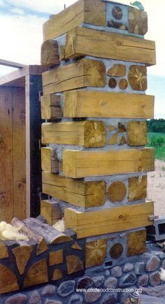 a large stack of wooden logs sitting on top of a pile of rocks next to a building