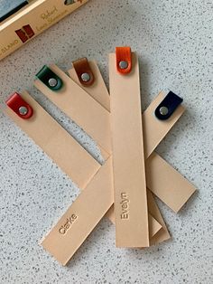 four pieces of leather with name tags attached to them sitting on a table next to a book