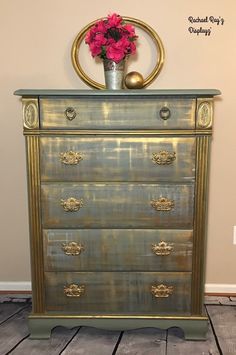 a gold painted dresser with pink flowers in a metal vase on it's top