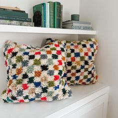 two crocheted pillows sitting on top of a white shelf