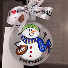 a glass ornament with a snowman on it and i love football written on the front