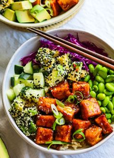 two bowls filled with vegetables and tofu next to chopsticks on a table