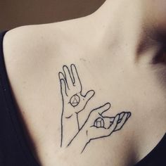 a woman with a tattoo on her chest holding up the hand that is in front of her