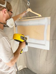 a man using a power drill to paint a piece of art on the wall with glue