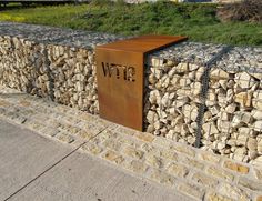 a metal box sitting on the side of a stone wall next to a grass covered field