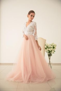 a woman in a long pink dress standing next to a chair