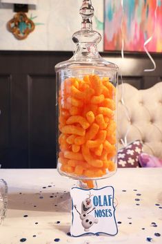 a glass jar filled with carrots sitting on top of a table next to a sign