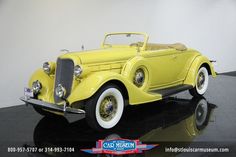 an old yellow car is on display in a museum