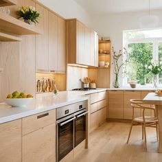 a kitchen with wooden cabinets and white counter tops, along with a bowl of fruit on the table