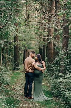 a pregnant couple standing in the woods together