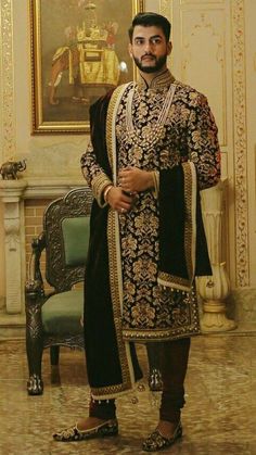 a man in a black and gold outfit standing in front of a painting on the wall