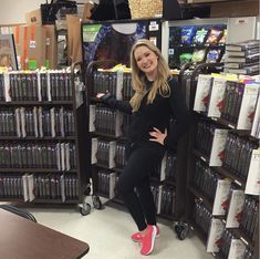 a woman standing in front of a large amount of dvd's