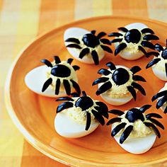 deviled eggs with black and white decorations on an orange tray, ready to be eaten