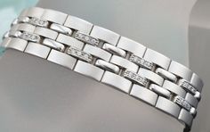 GENTS SIMULATED DIAMONDS BRACELET IN 14 KARAT WHITE GOLD DESIGN FOR JEWELRY SHOW. SKU-ART2 SETTING INFORMATION METAL ---------------14 KARAT WHITE GOLD SETTING -----------------PRONG SET FINISH------------HIGH POLISH AND SATIN FINISH WIDTH------------------------14 MM WEIGHT-47.5 GM SIMULATED DIAMONDS INFORMATION QUANTITY------------------------72 SHAPE-----------------------ROUND TOTAL WEIGHT----------------.75 CARAT CUSTOM ORDERS: Please feel free to contact us if you could not find the piece Silver Diamond Bracelet With Solid Link Construction, Luxury Diamond Bracelet For Anniversary, Anniversary Diamond Bracelet With Solid Link Construction, Modern Sterling Silver Bracelet With Diamonds, Modern Platinum Bracelets With Single Cut Diamonds, Modern Platinum Bracelet With Single Cut Diamonds, Modern Cubic Zirconia Diamond Bracelet, Modern Polished Faux Diamond Bracelet, Luxury Silver Diamond Bracelet With Solid Link