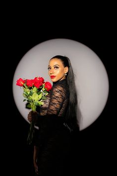 a woman with long hair holding roses in front of a black and white circle background