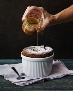 a person pouring syrup on top of a cake