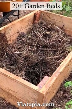 a wooden box filled with lots of dirt and straw next to a garden bed full of plants