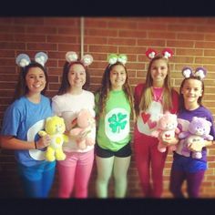 four girls are holding stuffed animals in front of a brick wall