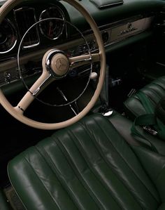 the interior of a classic car with green leather seats and steering wheel, including an automatic