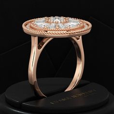 a rose gold ring with three diamonds in the center on top of a black box