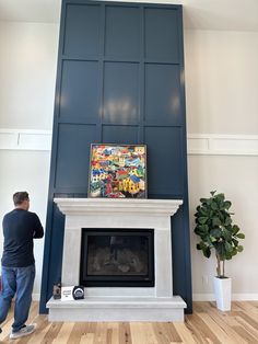 a man standing in front of a fireplace with a painting on top of the fire place