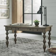 a wooden table sitting on top of a rug in front of a window with a potted plant