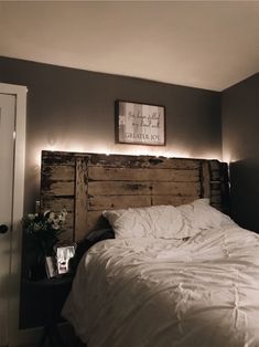 a bed with white comforter and pillows in a bedroom next to a wall mounted sign