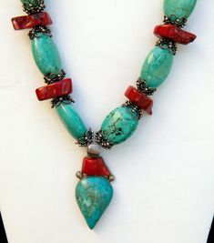 Stunning Turquoise and coral necklace with handmade pendant. Necklace is 18" with 2 1/2" pendant.  This gorgeous necklace has large turquoise and coral stone beads. The sterling silver bead caps have an intricate detailed design.  It is a show piece that will be the center for your outfit.  For many Americans, turquoise seems a distinctively American gemstone -- mined in Arizona, New Mexico, Colorado and Nevada, and with a long history in native American jewelry. But turquoise has been an important gemstone in many eastern cultures for thousands of years. This is reflected in the English name for the gem, since it was first brought to Europe by traders from Asia Minor.  This is the perfect necklace to add to your summer wardrobe and show off your tan! Original price $95.00 Photo Courtesy o Bohemian Turquoise Necklace With Red Coral, Handmade Turquoise Necklace With Red Coral, Bohemian Turquoise And Red Coral Necklaces, Bohemian Turquoise And Red Coral Necklace, Bohemian Turquoise Necklace With Red Coral For Gift, Bohemian Red Coral And Turquoise Jewelry, Bohemian Turquoise Beaded Necklace With Red Coral, Bohemian Red Coral Beaded Necklace In Turquoise, Bohemian Turquoise Beaded Necklaces In Red Coral