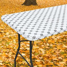 an ironing board sitting on top of a table covered in leaves next to a tree