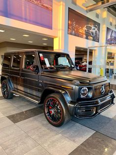 a black mercedes g - class parked in a showroom