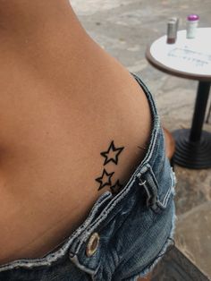 a woman's back with three stars tattoo on her left side ribcage