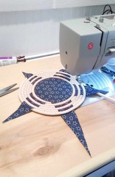 a sewing machine and some scissors on a wooden table with blue fabric in the shape of an ornament