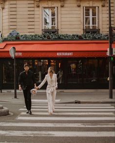 a man and woman crossing the street holding hands