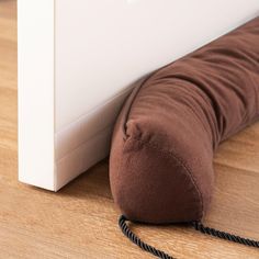 a brown pillow sitting on top of a wooden floor next to a white door frame