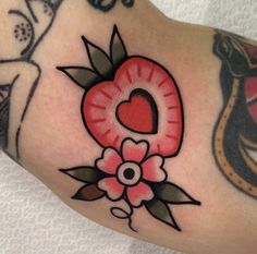 a close up of a person's arm with tattoos on it and a heart