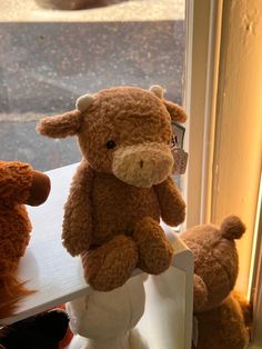 three stuffed animals sitting on top of a window sill in front of a door