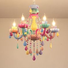 a colorful chandelier with candles on it in the middle of an empty room