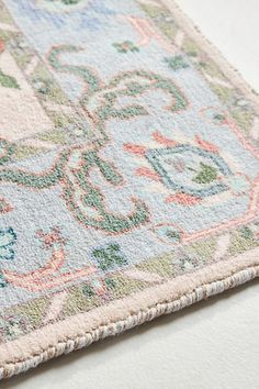 an area rug is laying on top of a white surface with blue, pink and green colors