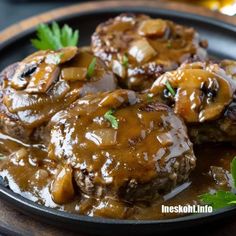 three meatballs covered in mushroom gravy on a black plate with green garnish