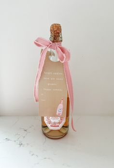 a bottle of wine with a pink ribbon tied around it and a message on the top