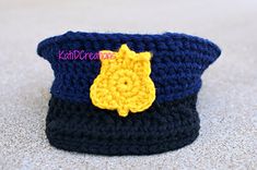 a crocheted hat with a yellow flower on the front and blue top, sitting on a white surface