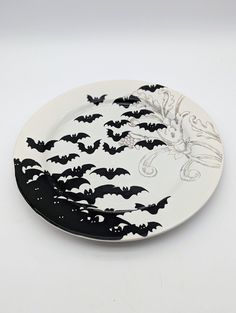 a black and white plate with bats flying in the sky on it's side