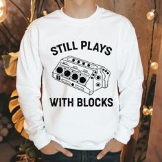 a man wearing a sweatshirt that says still plays with blocks