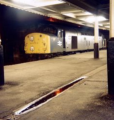 a yellow and silver train parked in a station