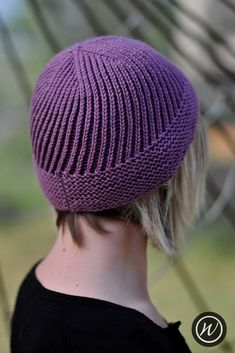 a woman wearing a purple knitted hat on top of her head and hair in the back