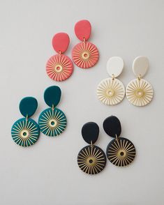 four pairs of earrings are shown on a white surface, one is red and the other is blue