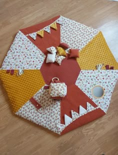 a patchwork table top with several pieces of fabric on the floor next to it