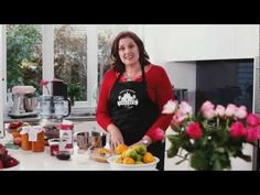 a woman standing in front of a counter filled with fruit and jams on it