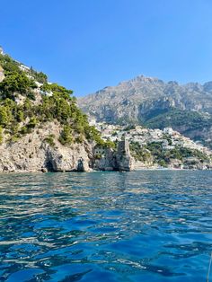 the water is crystal blue and there are mountains in the background